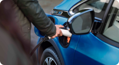 Man at a charging station inserting the charging unit into his blue GM EV