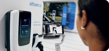 Une femme à une station de recharge regarde le chargeur de VÉ Ultium avant de l’utiliser.