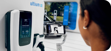 Woman at a charging station looking at the Ultium EV charging unit before using it